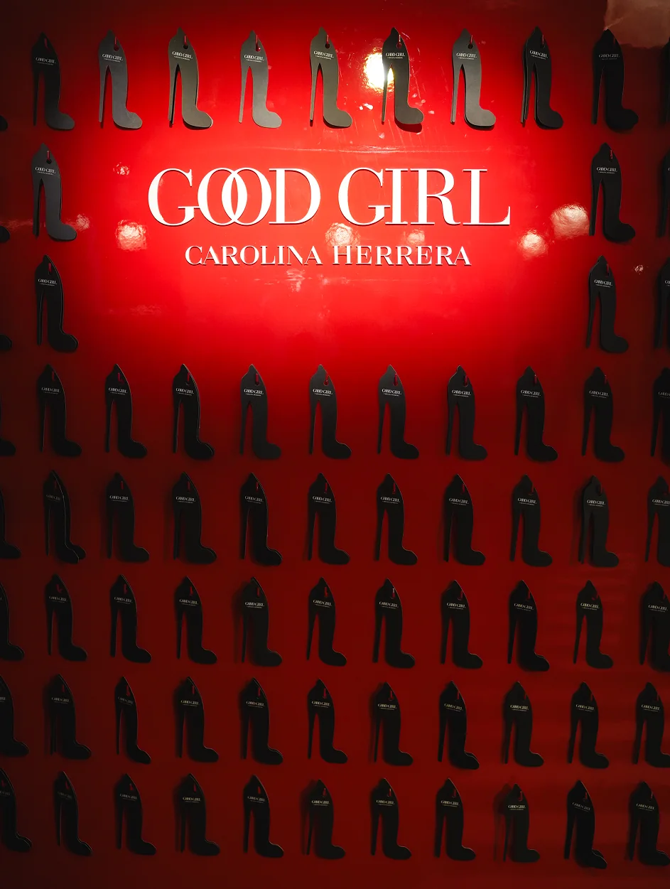 Carolina Herrera Good Girl fragrance display against a red wall